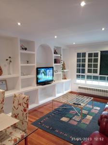 sala de estar con TV, mesa y sillas en AR Villa Rica Apartment en Santa Comba