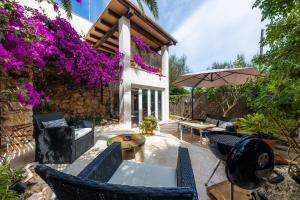 - une terrasse avec des chaises, un parasol et des fleurs dans l'établissement Cel Pins, à Portopetro