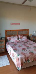a bedroom with a bed with a floral bedspread at SeeBos Holiday Home in Port Edward