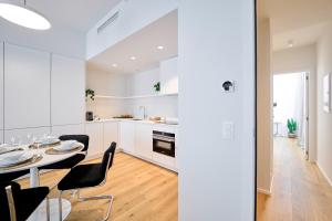 a white kitchen and dining room with a table and chairs at Place du Grand Sablon in Brussels