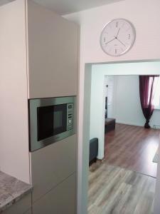 een woonkamer met een klok aan de muur en een magnetron bij Štýlový apartmán v Šamoríne in Šamorín