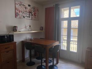 d'une salle à manger avec une table, des chaises et une fenêtre. dans l'établissement Nid douillet t3 au coeur des remparts, à Aigues-Mortes