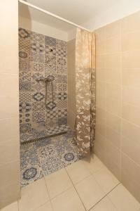 łazienka z prysznicem i ścianą wyłożoną kafelkami w obiekcie Tagyon Birtok Hordó Apartman w mieście Tagyon