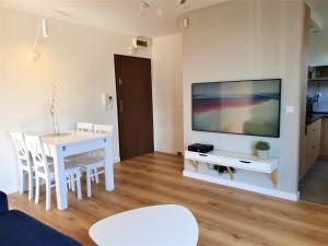 a living room with a table and a tv on a wall at APARTAMENT QUEEN KARWIA in Karwia
