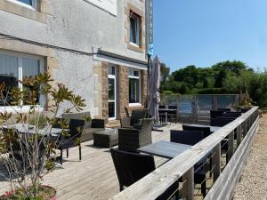 a wooden deck with chairs and tables on a building at Hotel Restaurant Le Phare in Perros-Guirec