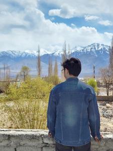 a man is looking out at the mountains at Norbooling HomeStay, Leh Ladakh in Leh