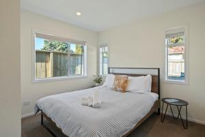a bedroom with a large bed with two windows at Cosy and Central in Taupo