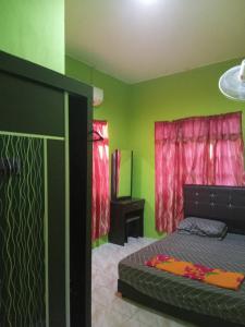 1 dormitorio con 1 cama con paredes verdes y cortinas rojas en Rosma homestay, en Kampong Ru Sepuloh