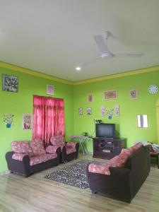 Sala de estar con 2 sofás y TV en Rosma homestay, en Kampong Ru Sepuloh
