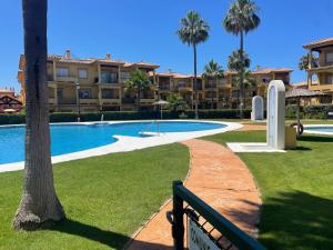 a resort with a swimming pool and palm trees at Margaritas 27 in Chiclana de la Frontera