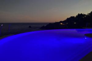 a blue swimming pool next to the beach at night at Appart vue mer avec piscine in Saint-Raphaël +5 photos