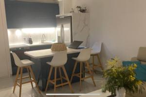 a kitchen with stools and a counter with a laptop on it at Appart vue mer avec piscine in Saint-Raphaël
