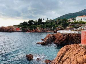 a body of water with houses on a rocky coast at Appart vue mer avec piscine in Saint-Raphaël