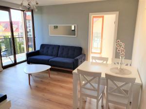 a living room with a blue couch and a table at APARTAMENT QUEEN KARWIA in Karwia