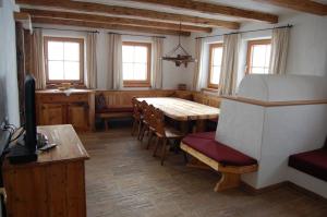 ein Esszimmer mit einem Tisch, Stühlen und Fenstern in der Unterkunft Salvenalm in Hopfgarten im Brixental