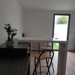 Un escritorio blanco con dos taburetes en una habitación en Guest House entre ville et océan, en La Rochelle