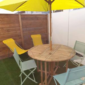 a wooden table with chairs and an umbrella at Guest House entre ville et océan in La Rochelle