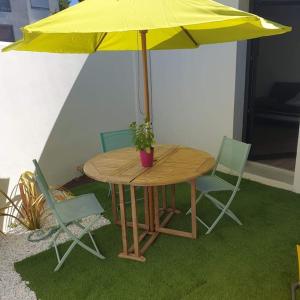 une table et des chaises avec un parapluie jaune dans l'établissement Guest House entre ville et océan, à La Rochelle