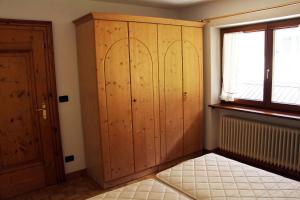 a room with a large wooden cabinet and a window at loft panorama Tre cime Dobbiaco Cortina in Dobbiaco