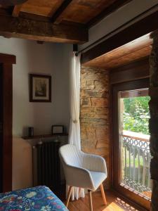 um quarto com uma cadeira branca ao lado de uma janela em Casa Rural Chao de Castro em Ríodeporcos