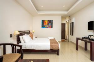 a bedroom with a bed and a desk and a television at Nexstay Ministers Mansion in Kanthalloor