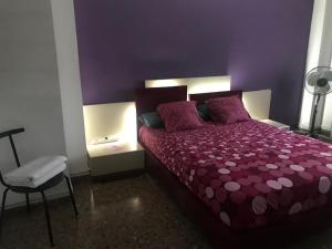 Dormitorio púrpura con cama y silla en Apartamento cómodo y espacioso con parking, en Valencia