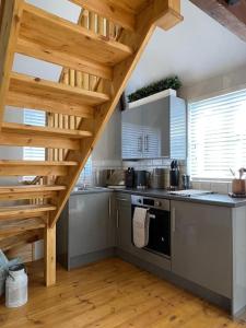 cocina con escalera de madera en una habitación en The Shack - Thatched Self Contained Annex, en Collingbourne Ducis