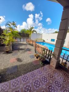 a patio with a pool and a fence and plants at Fina Villa Apartments - Mont choisy in Mont Choisy