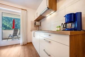a kitchen with white cabinets and a view of a balcony at Talblick Apartement 3 in Laion +13 photos