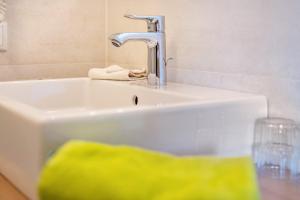 a white sink with a faucet and a glass at Talblick Apartement 3 in Laion