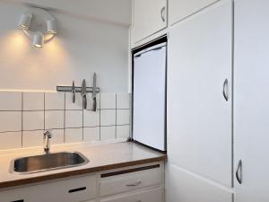 cocina con fregadero y armarios blancos en One Bedroom Apartment In Rdovre, Trnvej 41b, 2, en Rødovre