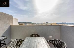 d'une table et de chaises sur un balcon avec vue. dans l'établissement Beautiful, 2BR penthouse with private outdoor area by 360 Estates, à San Pawl il-Baħar