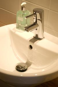- un lavabo avec une bouteille de savon et un téléphone portable dans l'établissement Grasshopper Hotel Glasgow, à Glasgow