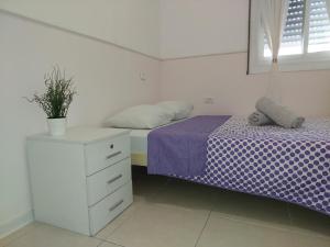 a bedroom with a bed and a dresser with a plant on it at magical apartment close to the Baha'i Gardens in Haifa