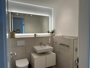 une salle de bain avec un lavabo, des toilettes et un miroir dans l'établissement Deluxe Apartment Goldsteinkoje 2, à Bad Nauheim 29 autres photos