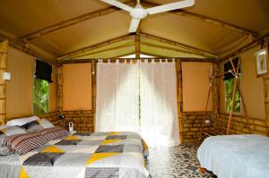 a bedroom with two beds and a ceiling fan at Aguas Claras Bamboo Ecolodge in Guaduas