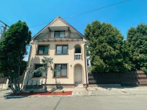 a white house with a balcony on a street at Cozy Glen - Private Villa, Parking and BBQ in Târgu-Mureş