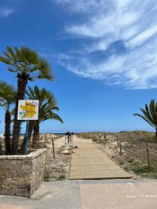 a boardwalk leading to the beach with palm trees at Beautiful apartment 1 minute walk to the beach in Puerto de Sagunto