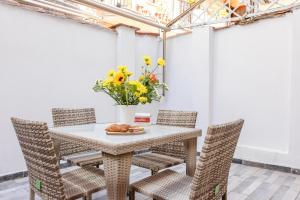 uma mesa com cadeiras e um vaso com flores amarelas em Art House Centro Storico Luxury Apartment em Roma