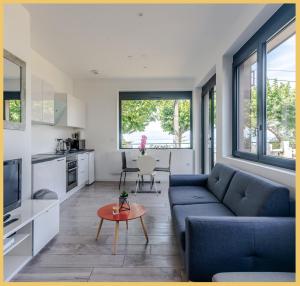 a living room with a blue couch and a table at Appartement Cozy 1 Panoramique Lac Léman Thonon-Les-Bains in Thonon-les-Bains