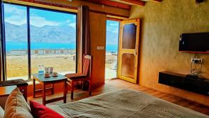 a bedroom with a bed and a table with a view at Mystic Pangong in Spangmik
