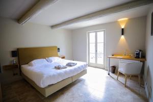 a bedroom with a bed and a desk and a window at Hotel La Bastide d'Eygalières in Eygalières