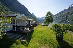 a house in a field with mountains in the background at Geirangerfjorden Feriesenter in Geiranger