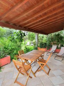 a wooden table and chairs under a wooden pergola at Pareja Apartments in Orosei
