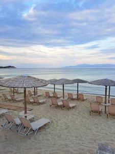 a group of chairs and umbrellas on a beach at Elegance apartment in Paleo Tsifliki