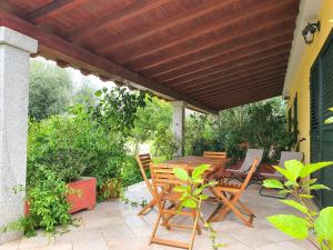 a wooden table and chairs under a wooden pergola at Pareja Apartments in Orosei