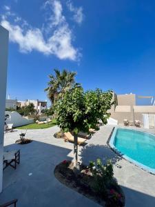 a swimming pool with a tree in a yard at Santorini Villatzio Suites in Mesaria