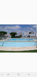 two photographs of a large swimming pool at Urbanización las Torres Apartamento in Chiclana de la Frontera