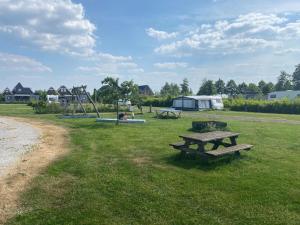 einen Park mit zwei Picknicktischen und einem Spielplatz in der Unterkunft Modern chalet in the Frisian countryside in De Veenhoop