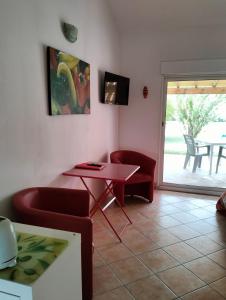 een woonkamer met een rode tafel en stoelen bij Petit Mazet Fruits rouges in Eyragues